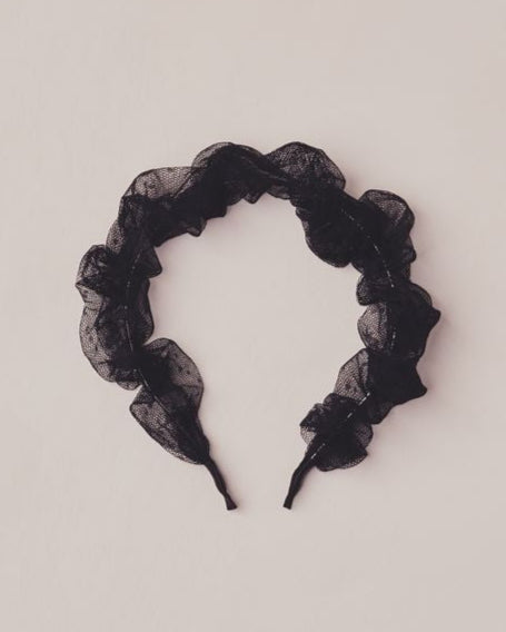 Black tulle headband on a light beige background