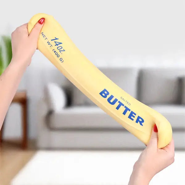 Yellow block of butter held by two hands with a blurred indoor background