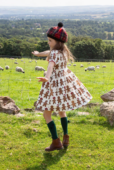 little girl modeling a gingerbread dress and she is twirling around while doing it. 