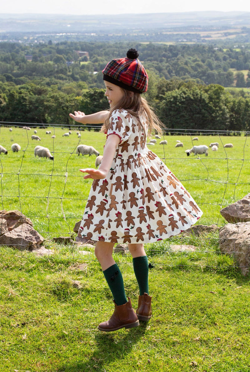 little girl modeling a gingerbread dress and she is twirling around while doing it. 