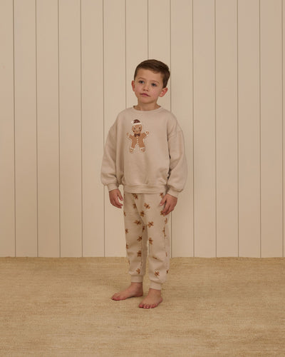 Boy modeling gingerbread sweatsuit , gingerbread sweatshirt and tiny gingerbread men all over the pants. 