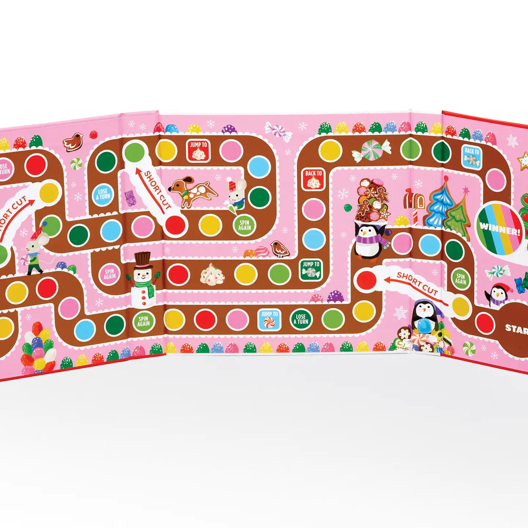A colorful children's board game set displayed on a white background. The board features a whimsical pink and brown path with round multicolored spaces, holiday-themed illustrations, and multiple game pieces including penguins, a snowman, and a Christmas tree.