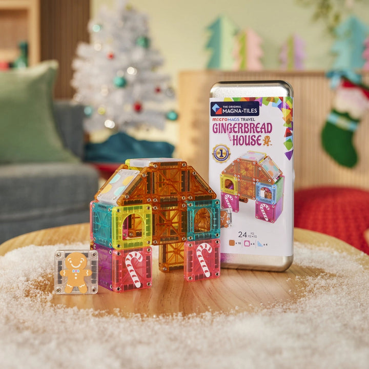 Colorful magnetic building blocks and a gingerbread house-themed packaging on a table with a festive background.