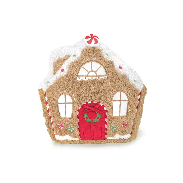 A gingerbread house plush toy with a brown textured body, white faux icing on the roof and trim, a red door with a green wreath, and small candy decorations, shown on a plain white background.