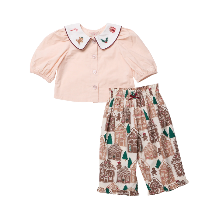 A two-piece baby outfit set featuring a pale pink short-sleeve top with a white Peter Pan collar decorated with small embroidered motifs, paired with cream-colored pants printed with a brown and green gingerbread house pattern.