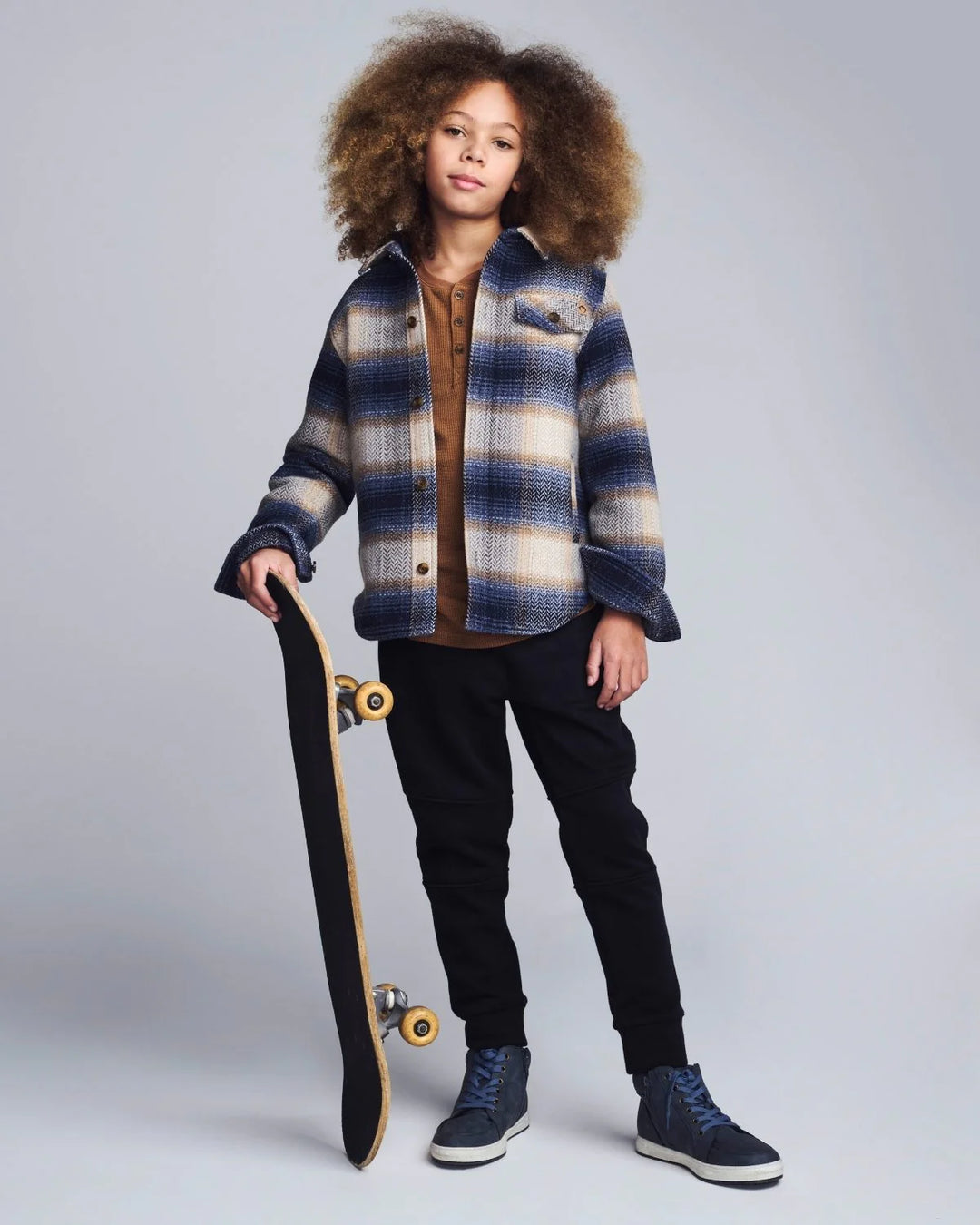 young boy wearing a hooded shirt with navy herringbone plaid