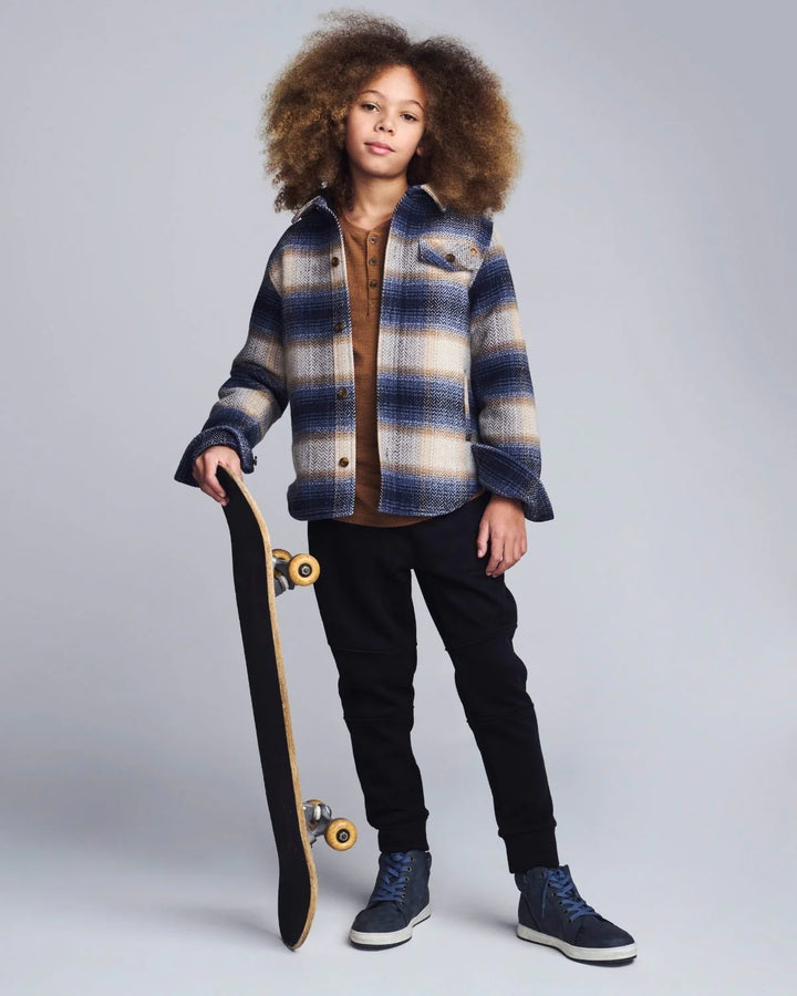 young boy wearing a hooded shirt with navy herringbone plaid