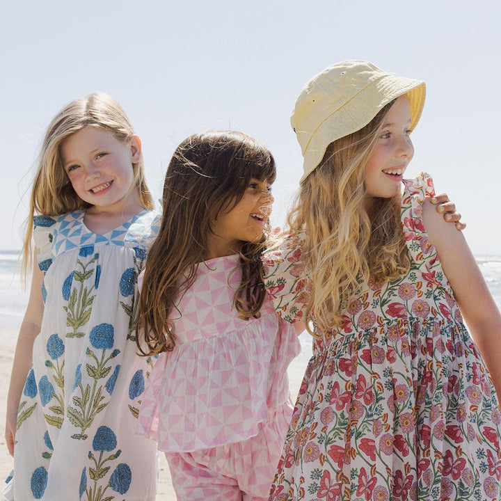 picture of all all three girls on the beach, each in a different print: pink geometric print, blue flowers and butterfly vine print. 