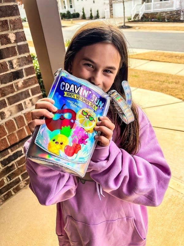 close up of the handbag and the fruits that are on the front of the bag and a little girl holding the bag. 