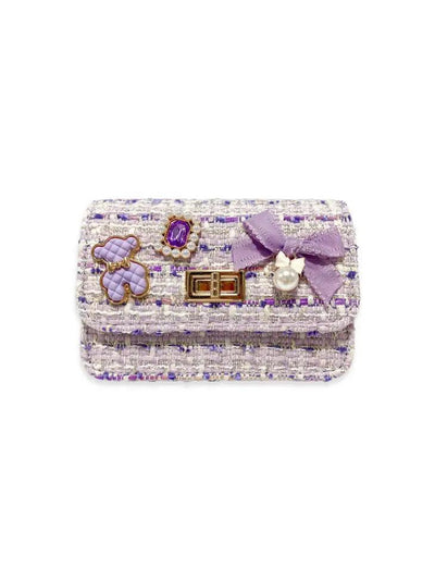 lavender and ivory tweed bag with bear charm and bead charm and lavender bow attached to the front of the flap of the bag. 