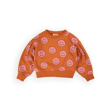 orange sweatshirt with pink smiley faces all over it. 