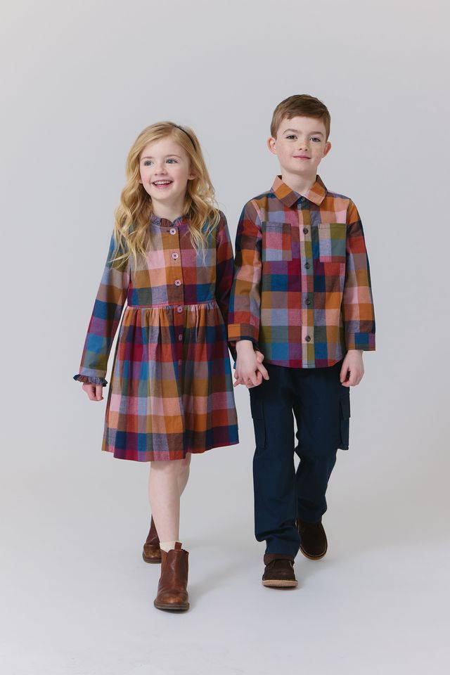 Two children wearing matching plaid outfits on a white background