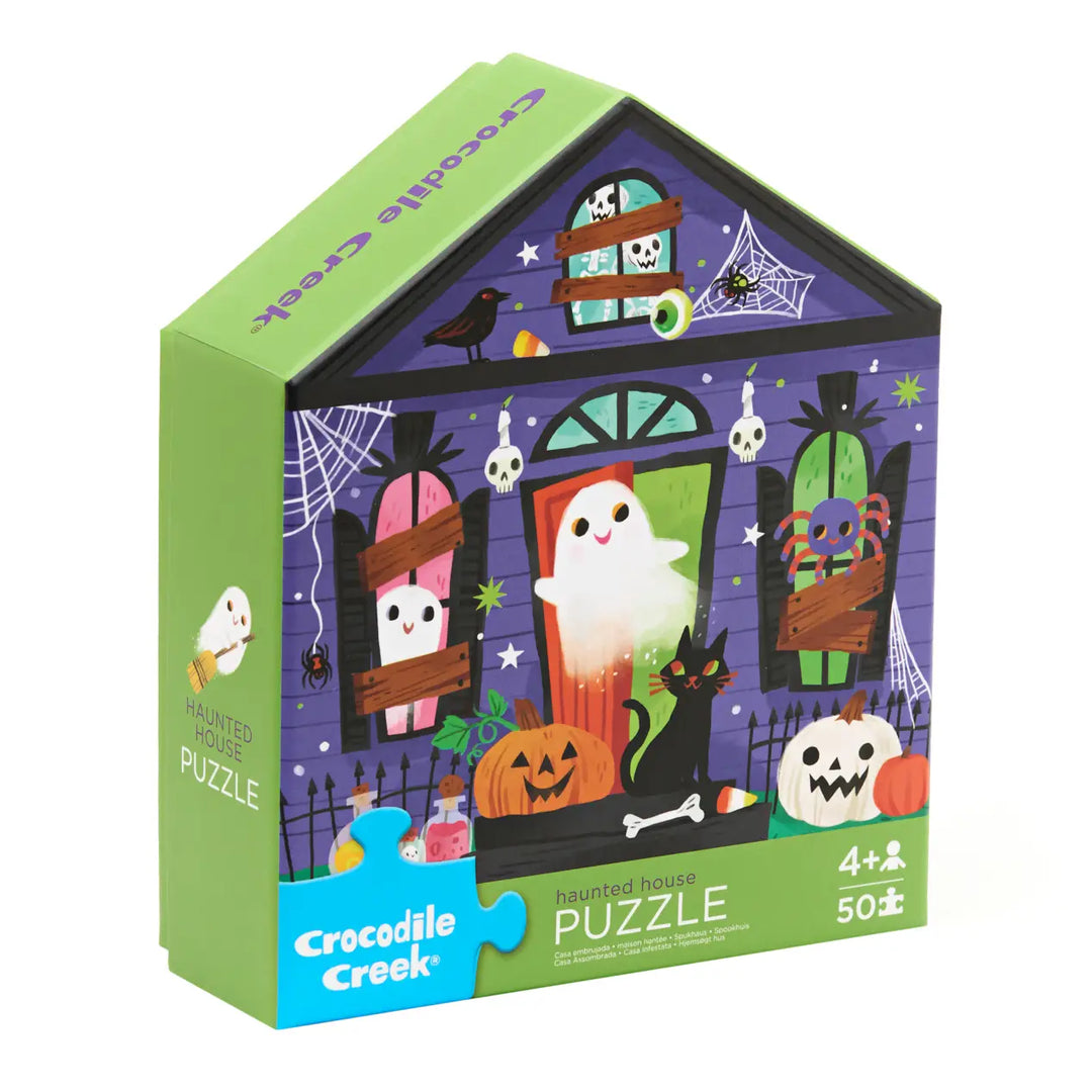 Crocodile Creek Halloween House jigsaw puzzle box, featuring a purple haunted house illustration with a ghost, pumpkins, spiderwebs, and a black cat on the front, with a green side panel showing the brand and 'Puzzle' text.