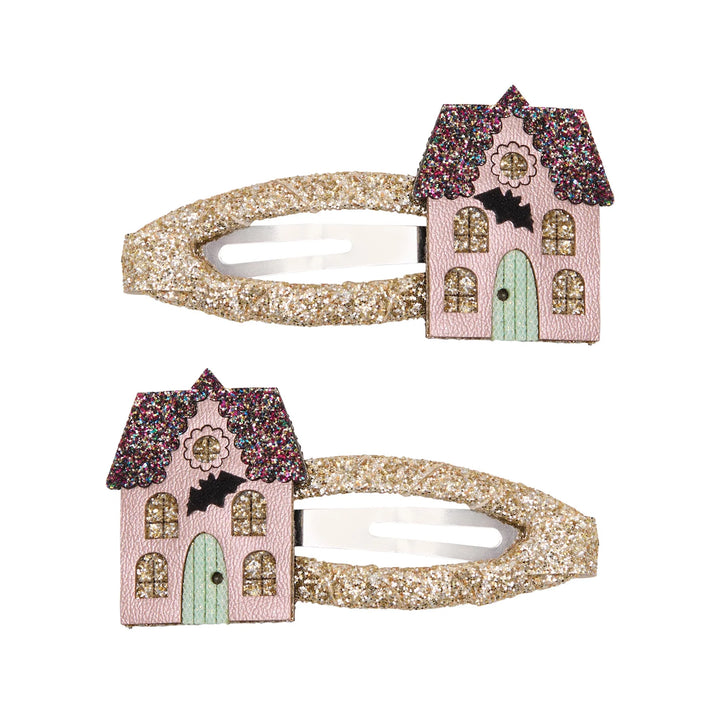 Two matching hair claw clips with glittery gold handles and pink haunted house decorations featuring a mint green door, gold windows, and a black bat on a white background.