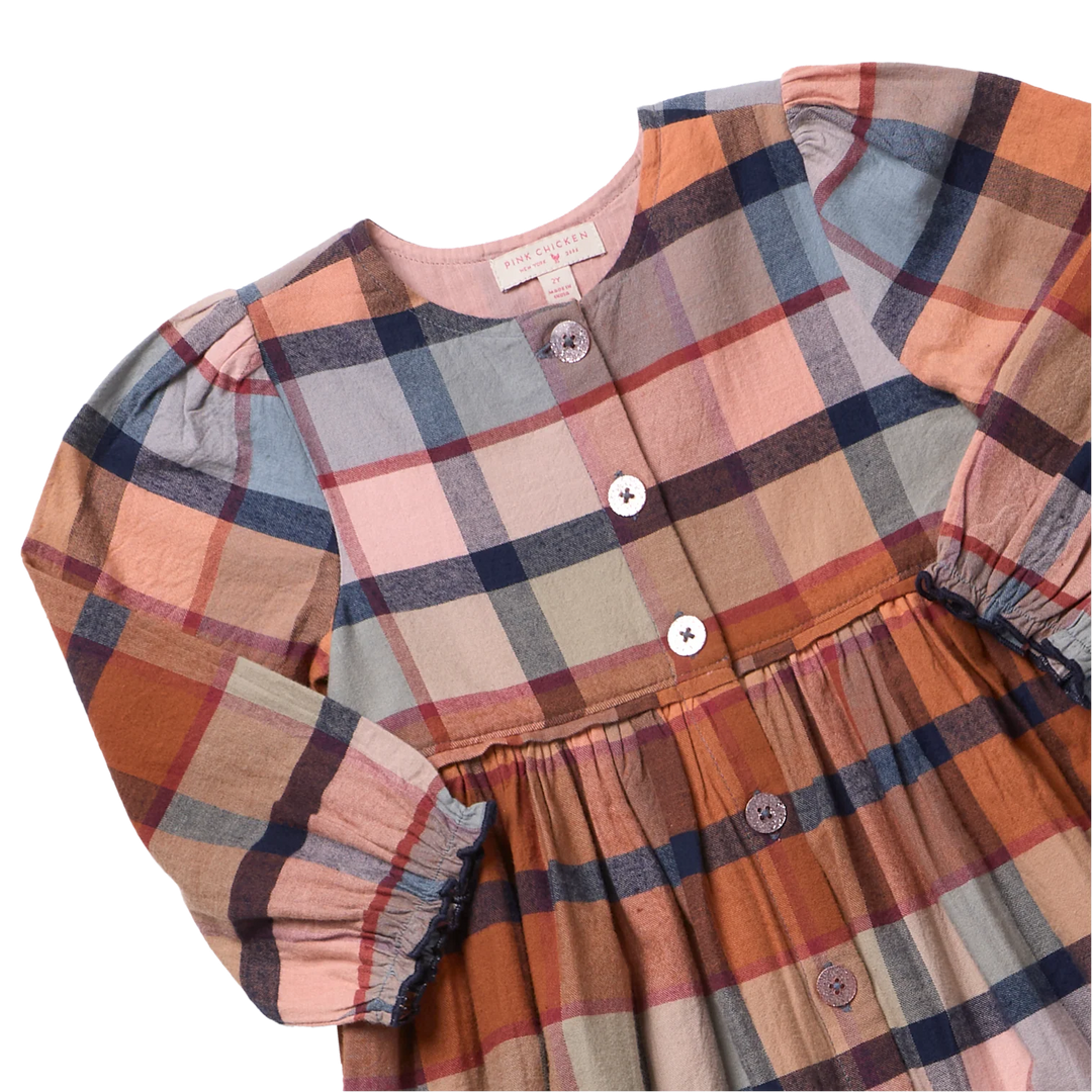 close up of long sleeve rust plaid dress with blue accents. 