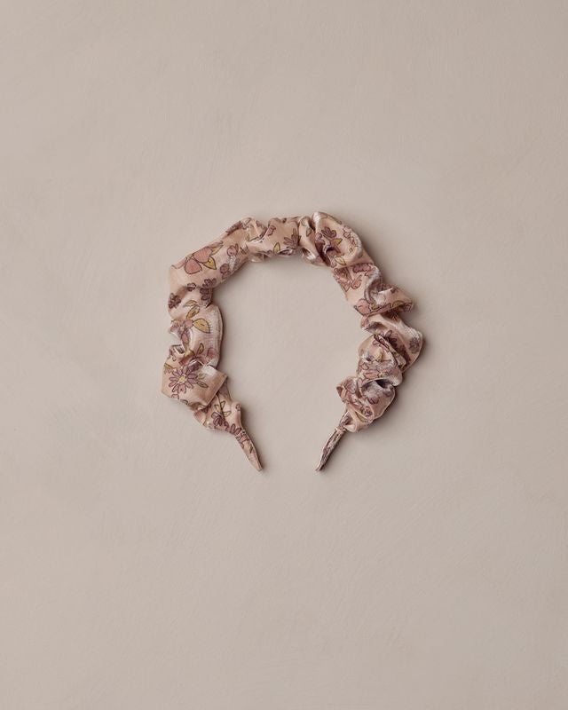 Floral patterned gathered headband on a beige background