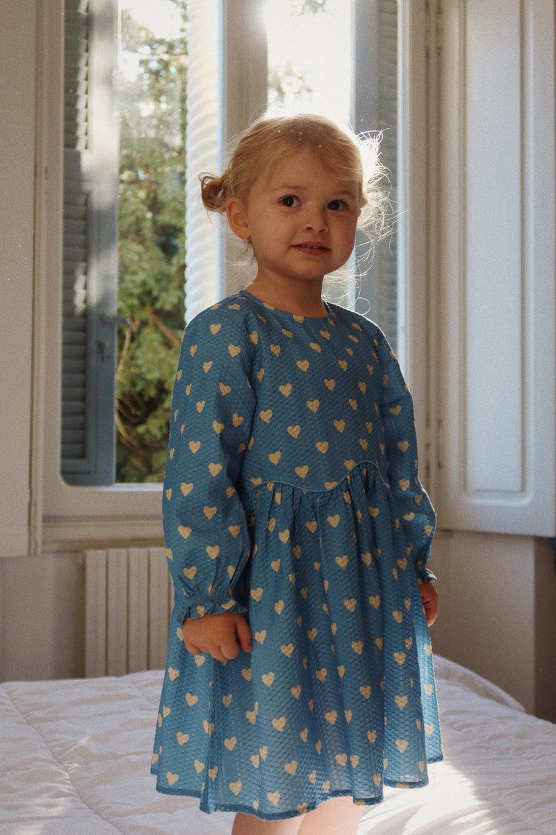 image of a little girl modeling the hearts dress with blousy sleeves . this picture shows how the dress hits at the natural waist is billowy in nature and has a soft full skirt