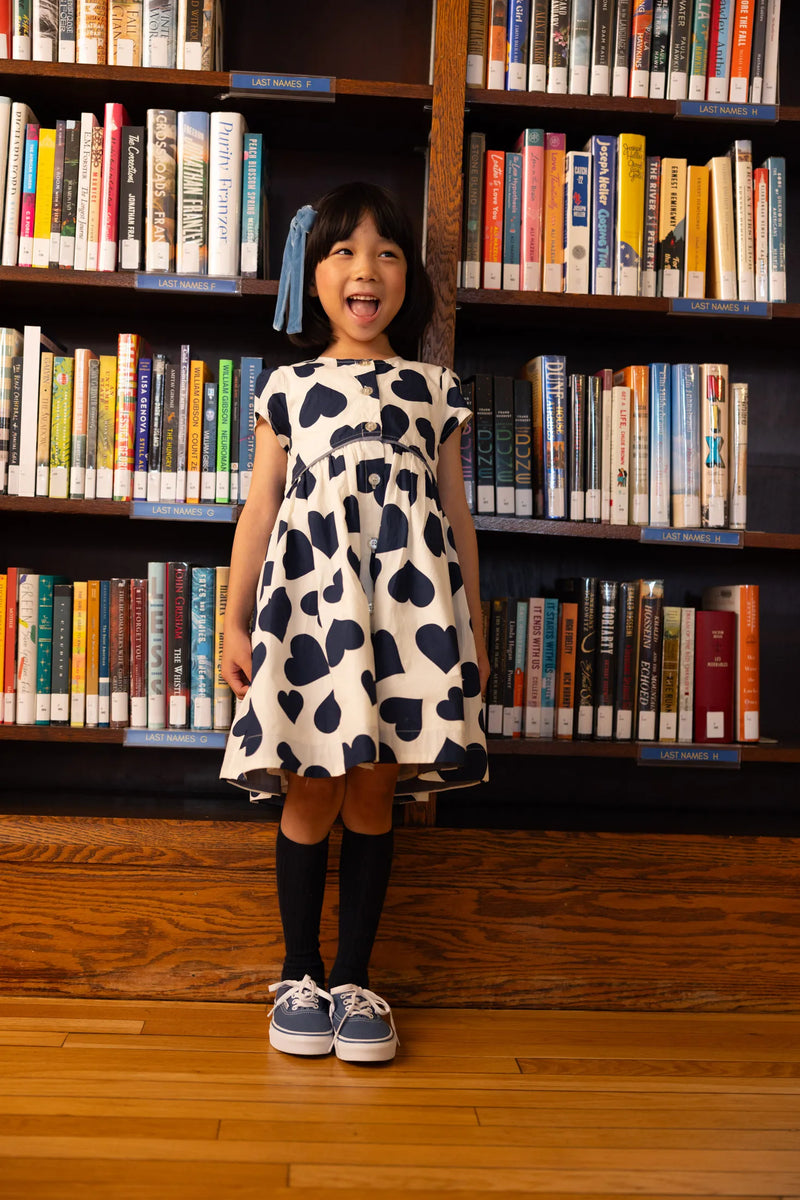 Little girl modeling the shirt dress with large navy hearts. 