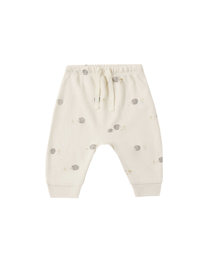 Off-white baby jogger pants with a small gray hedgehog print, featuring an elastic waistband and drawstring.
