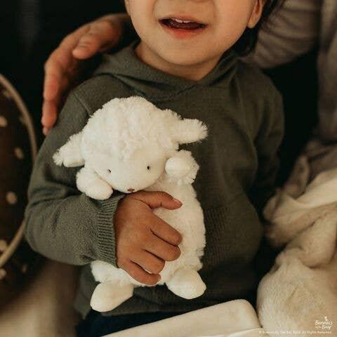 soft plush lamb, small in size. This pictures shows a small child hugging the lamb. 