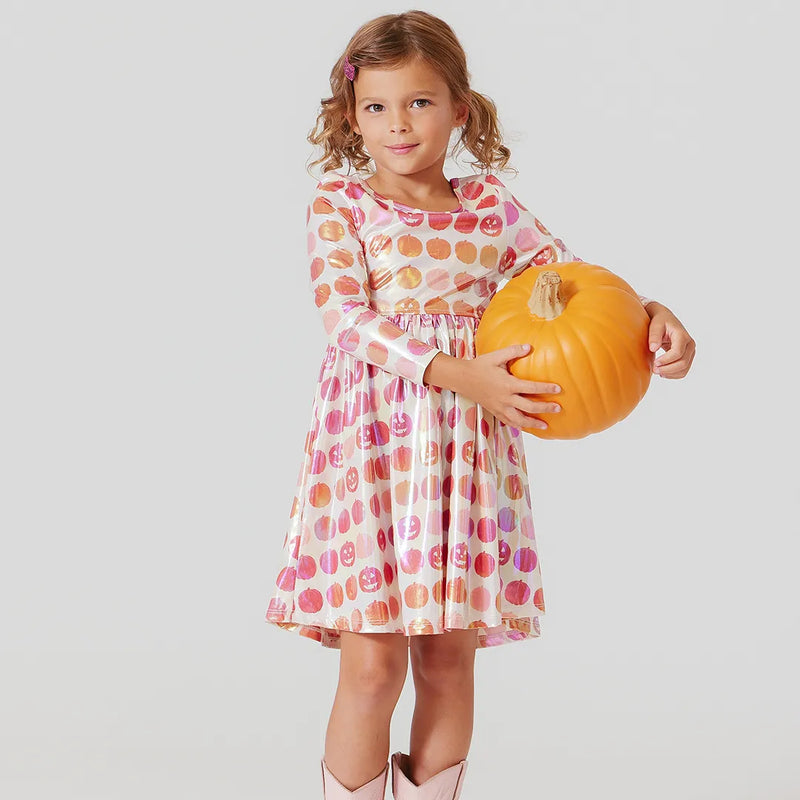 little girl is modeling the pumpkin dress while holding a pumpkin 