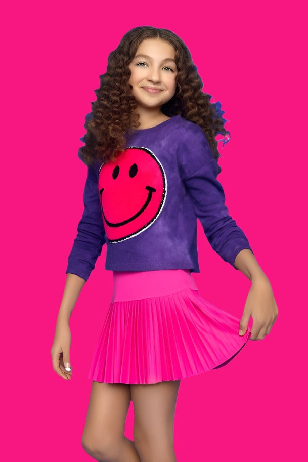 hot pink pleated skirt and purple sweatshirt with big pink smiley face on the center- modeled on the girl