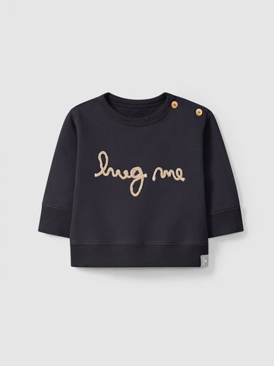 navy baby sweater that reads "hug me". two wooden buttons on the shoulder.