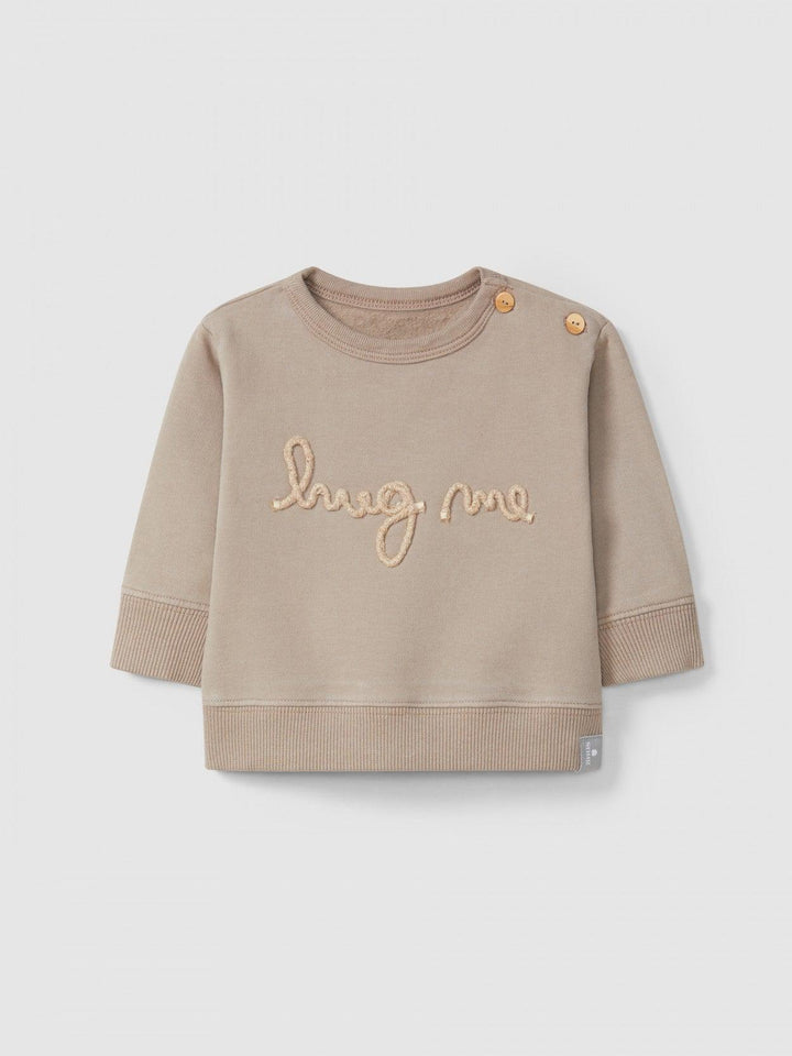 taupe sweater that reads"hug me" in light pink embroidery. two buttons on the top for easy changing. 