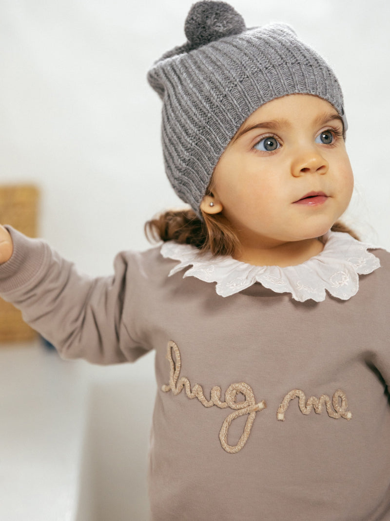 picture of baby modeling the taupe sweater with hug me written across the chest