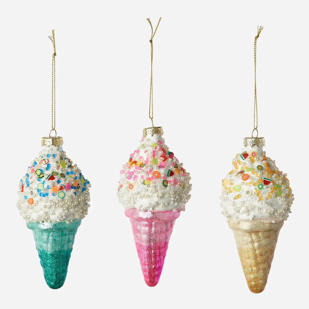 Three ice cream cone ornaments hanging side by side on a light gray background. Each ornament has a white textured scoop topped with colorful sprinkles and a glittery cone in teal, pink, and gold.