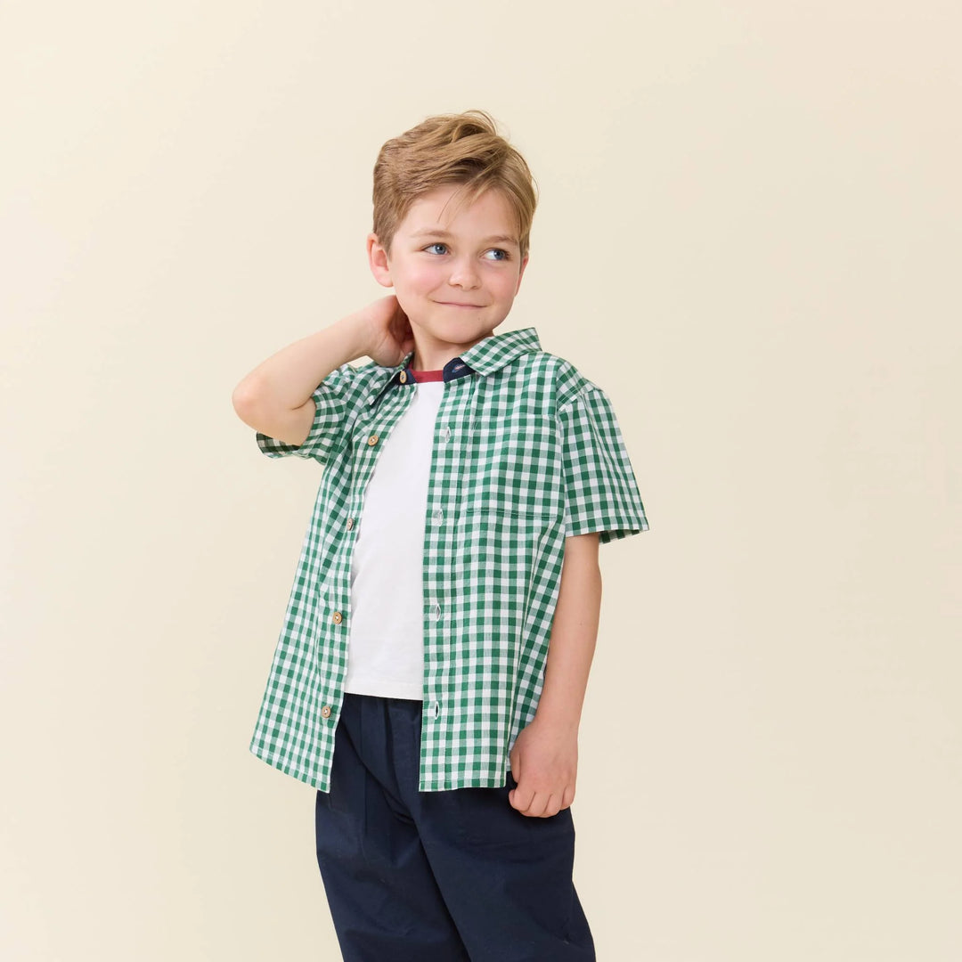 Child wearing a green checkered shirt on a beige background
