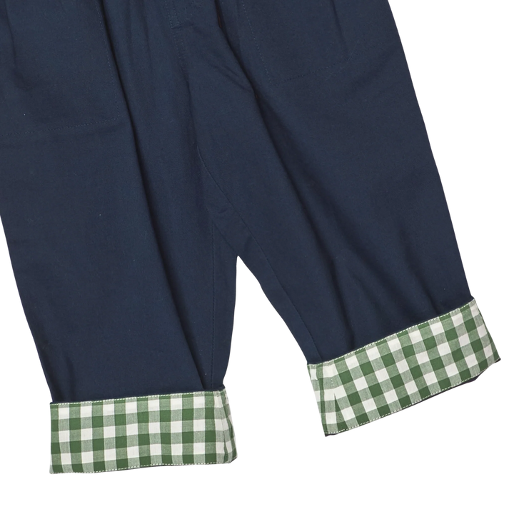 Close-up of navy pants with rolled cuffs showing a green and white gingham pattern.