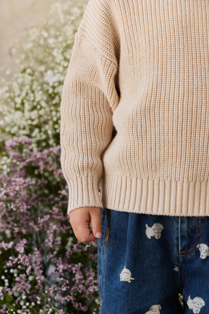 Person wearing a beige sweater with floral and plant background