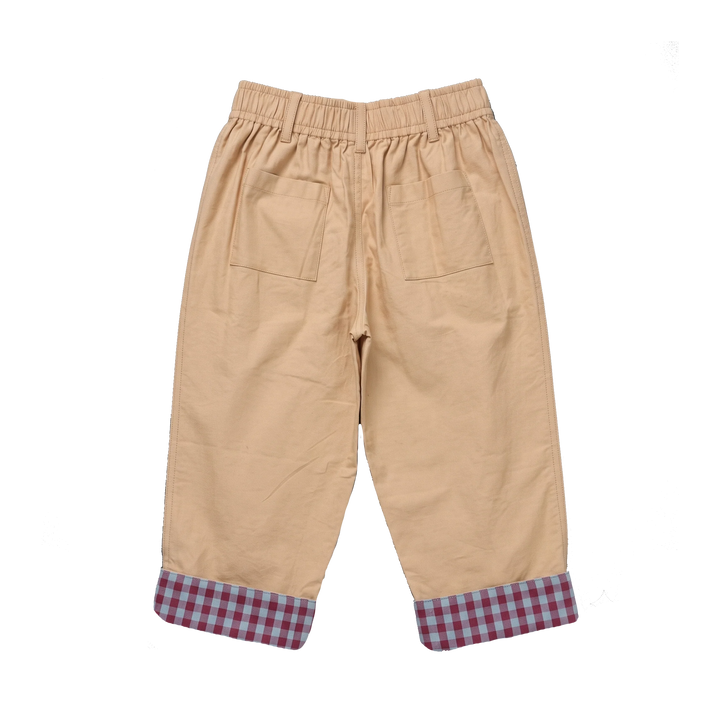A pair of beige  pants with an elastic waistband, two back patch pockets, and rolled cuffs showing a red and blue gingham pattern, photographed on a solid white background.