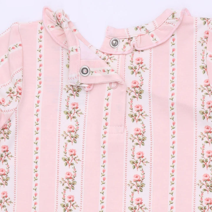 A close-up of a baby garment featuring vertical pink stripes and delicate pink rose floral prints with green leaves, accented by a ruffled collar and snap buttons.