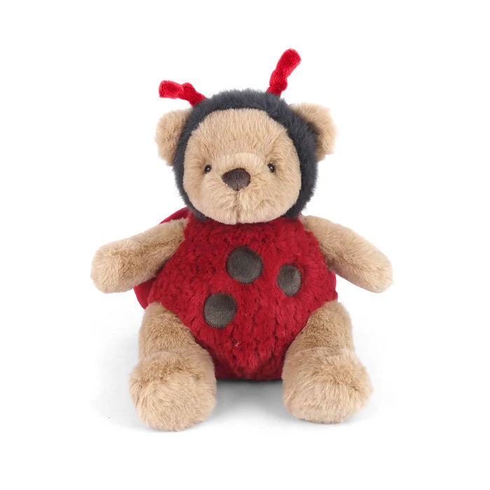 A plush teddy bear dressed as a ladybug, featuring tan fur, a red body with dark red spots, and a black head covering with red antennae, photographed on a clean white background.