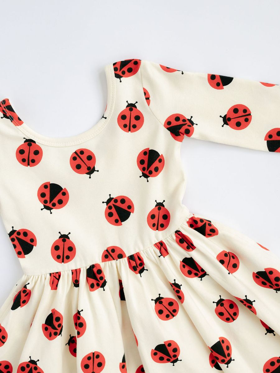 White dress with red and black ladybug pattern on a white background