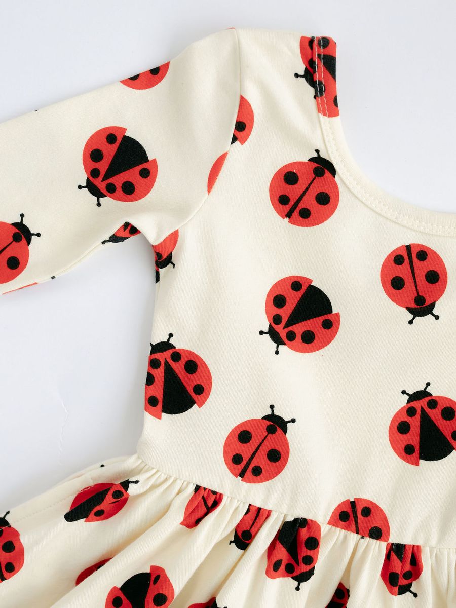 White dress with red and black ladybug pattern on a white background