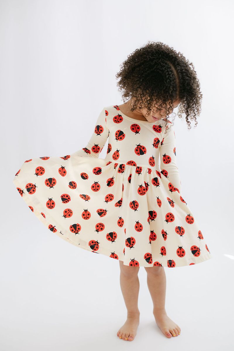 Child wearing a dress with ladybug pattern on a white background