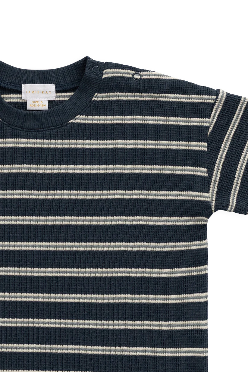 A close-up of a short-sleeve waffle-knit top with horizontal navy and off-white stripes, featuring a ribbed crew neck and a visible J.K