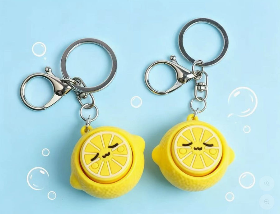 Two lemon-shaped keychains with a cute face design on a light blue background.