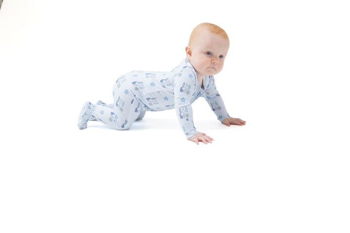 Baby in a blue patterned onesie crawling on a white background