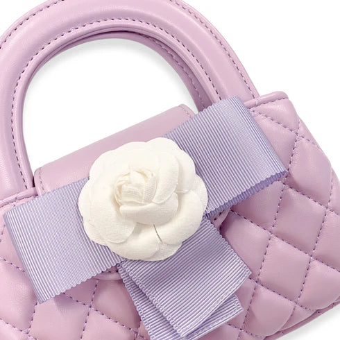 Pink quilted handbag with a white flower and ribbon detail on a white background