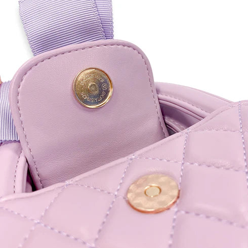 Close-up of a quilted purple handbag with gold buttons and a ribbon detail.
