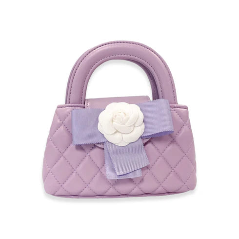 Small purple quilted handbag with a white flower and bow on a white background