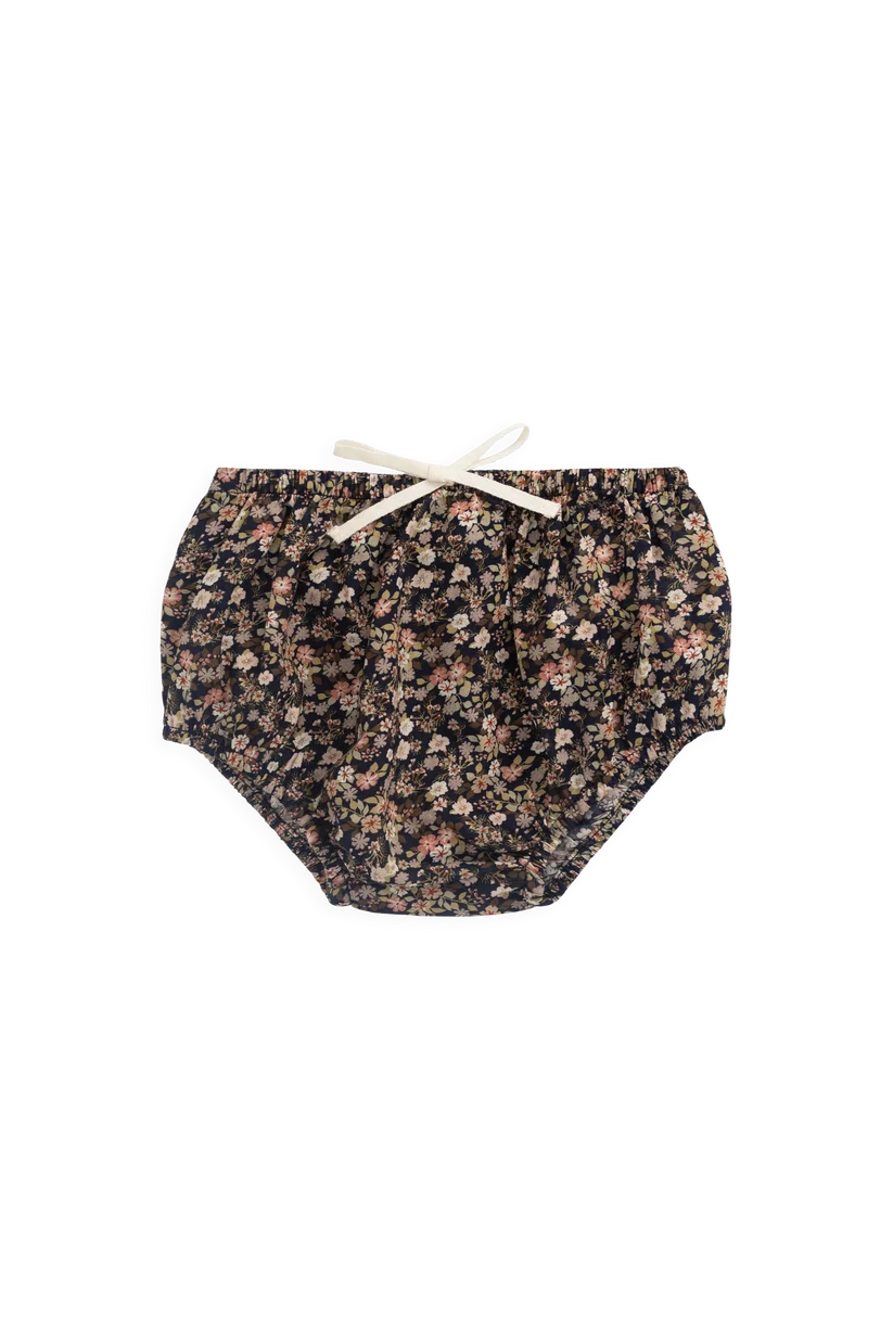 A pair of baby bloomers with a dense small floral print in black, pink, and beige, featuring an elastic waistband and a white bow tie.