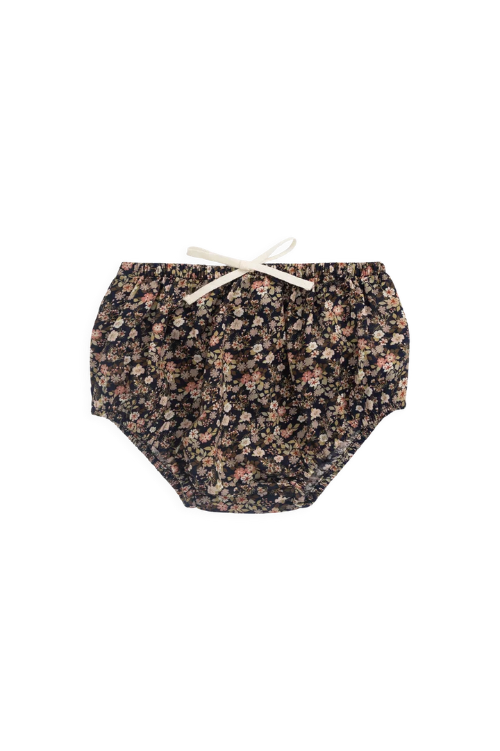 A pair of baby bloomers with a dense small floral print in black, pink, and beige, featuring an elastic waistband and a white bow tie.