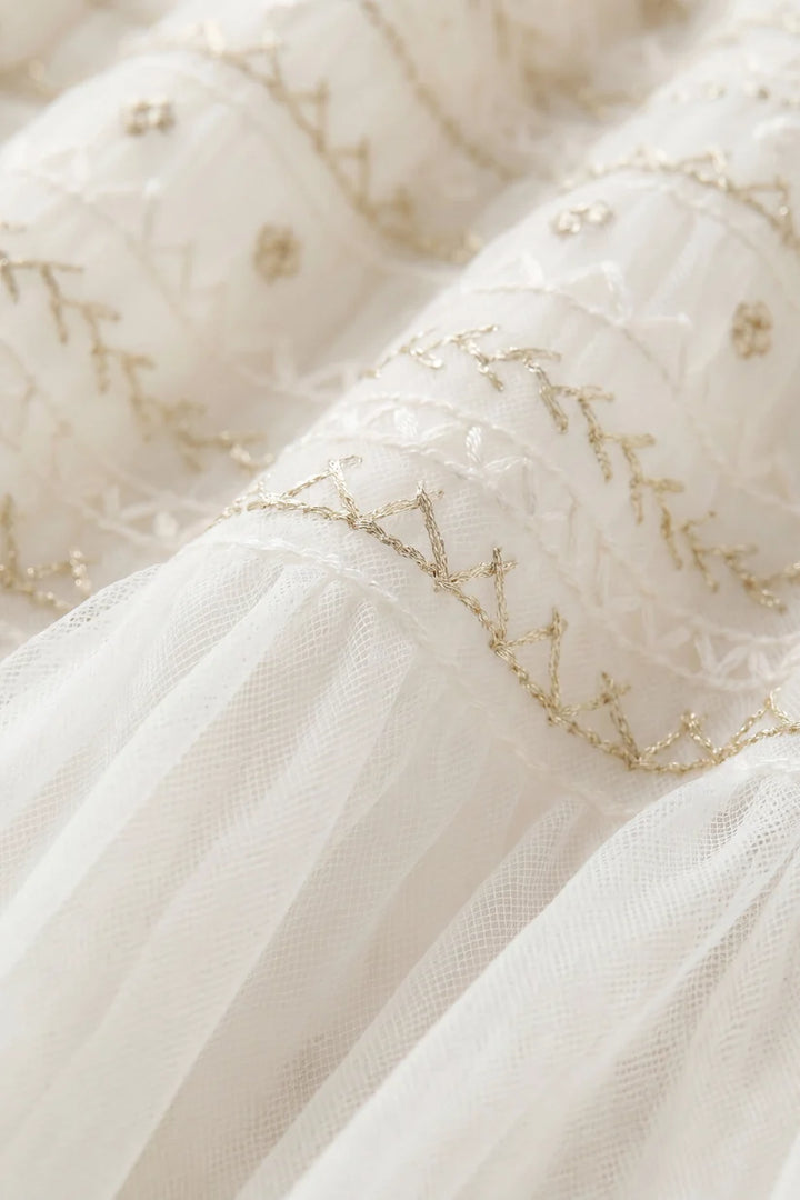 Close-up of a white dress with gold embroidery