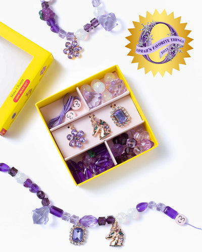 purple beads and charms in a yellow packaging box with compartments for all the beads. charms are rhinestone shaped 