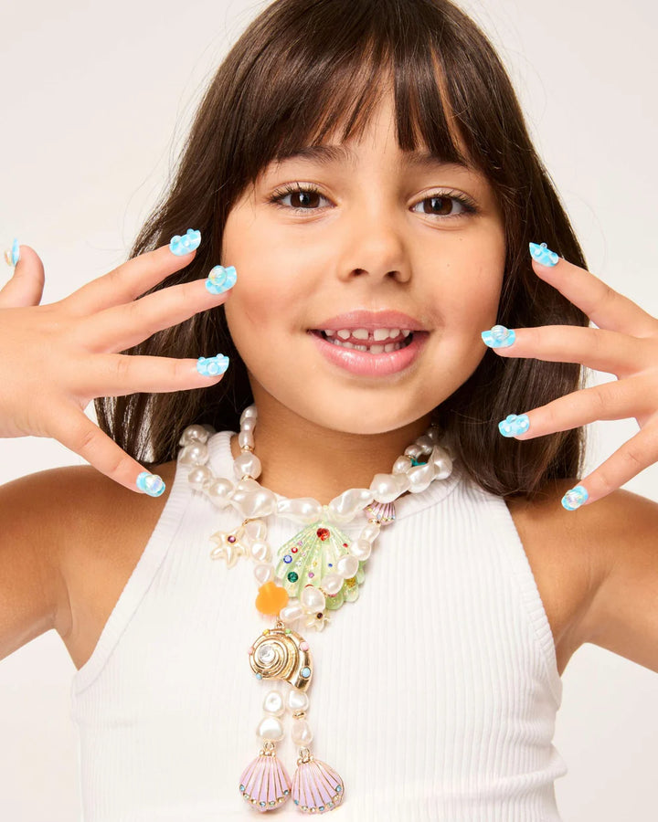 young girl modeling the press on nails with teal nails and a pearl on it. 